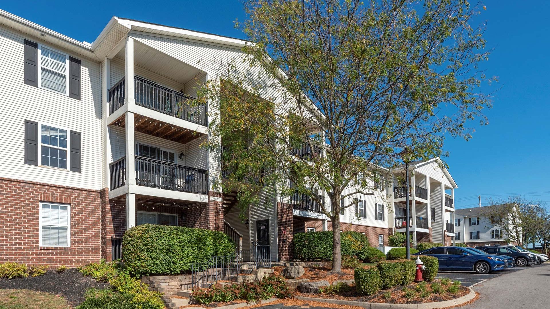 the exterior of an apartment complex with trees and bushes at The Sawmill Park