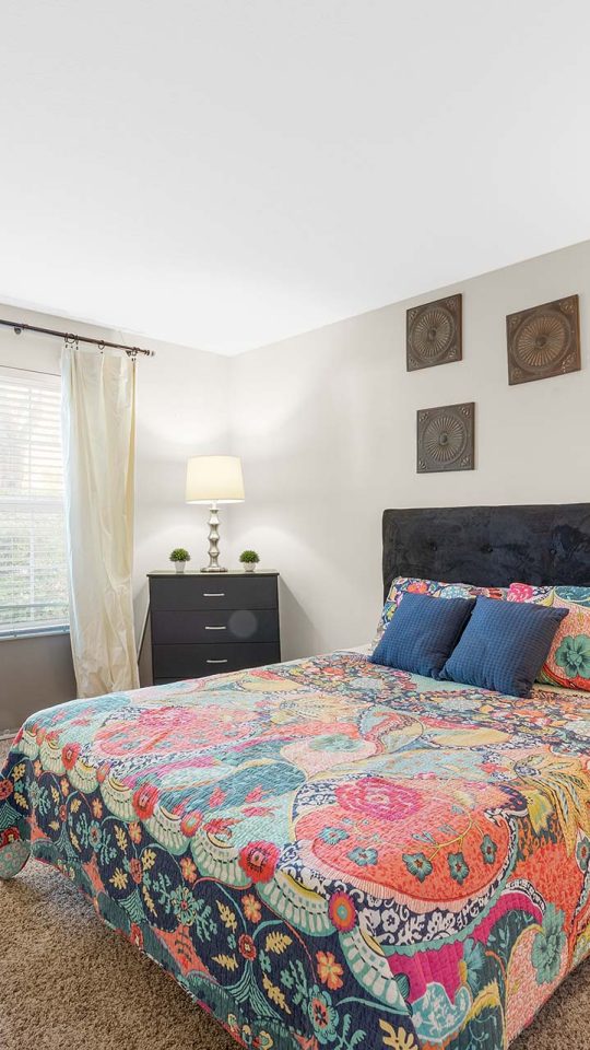 a bedroom with a colorful bed and a lamp at The Sawmill Park